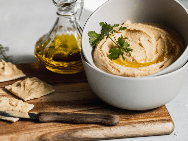 Hummus in a bowl next to olive oil and pita bread