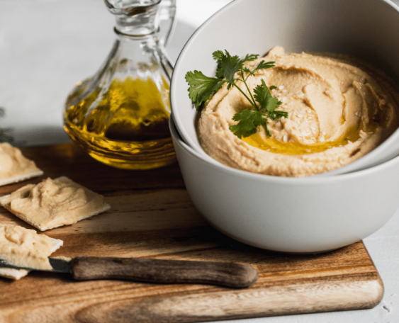Hummus in a bowl next to olive oil and pita bread